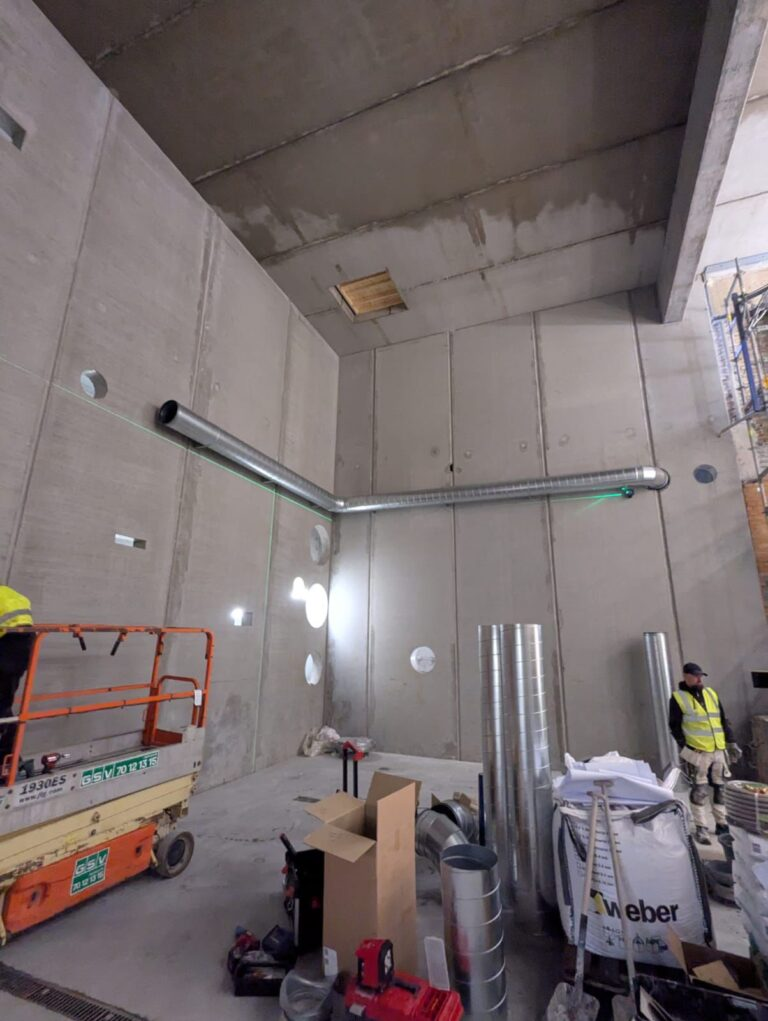 Montør på lift under kanalmontage i højloftet rum