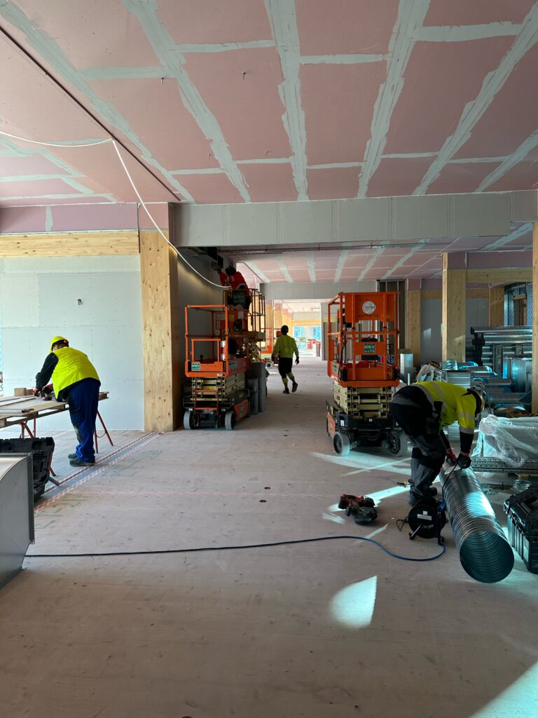 Montører arbejder fra sakselifte med kanalmontage