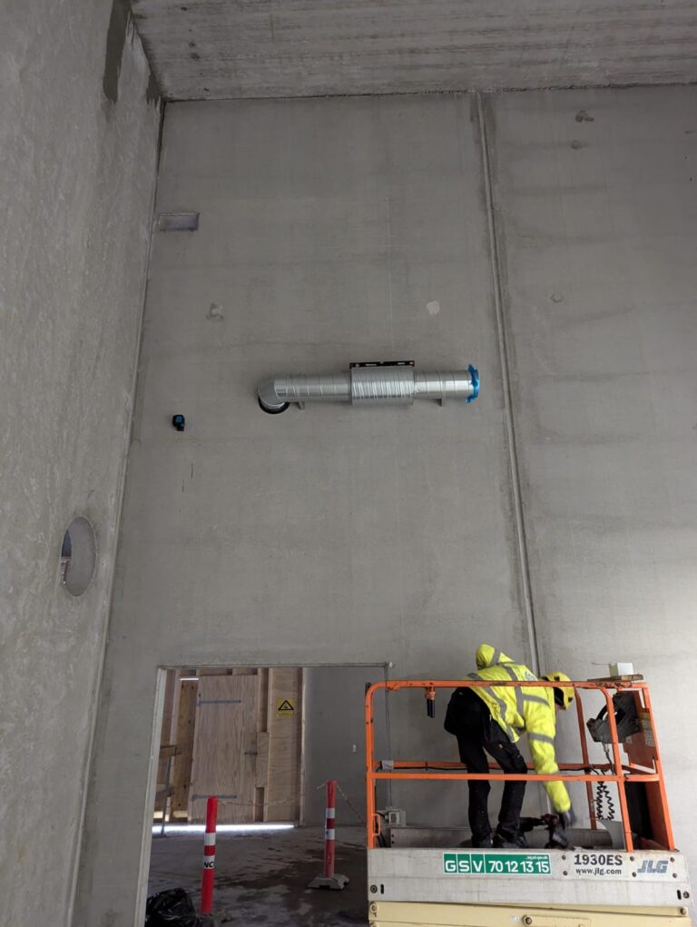 Lyddæmper og kanal monteret højt på betonvæg